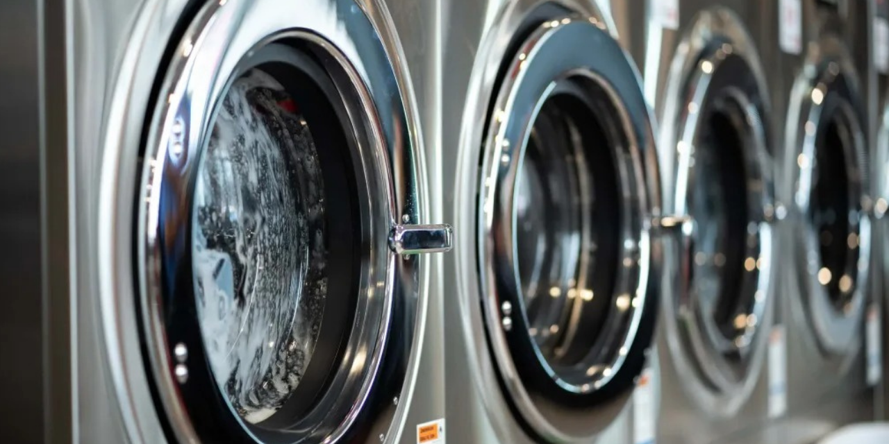 Single row of silver and gray commercial washing machines.