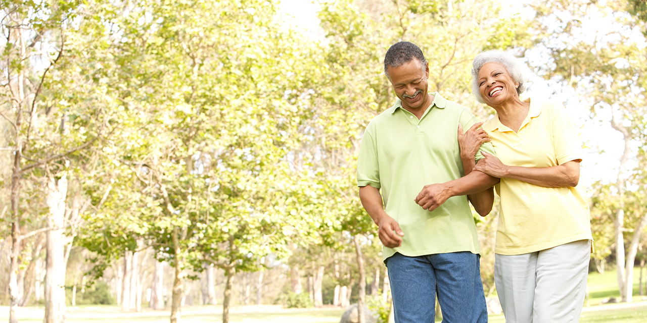 Couple walking arm in arm in a park.